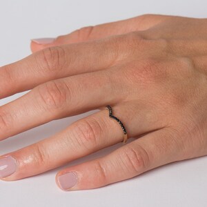 May include: A delicate gold ring with a V-shaped band set with black diamonds.