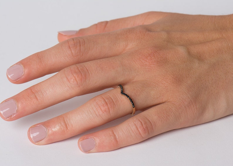 May include: A delicate gold ring with a V-shaped band set with black diamonds.