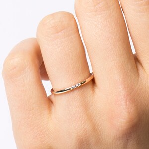 May include: A delicate gold band ring with three small diamonds set in a row.