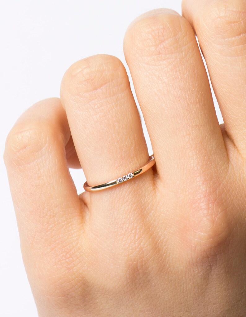 May include: A delicate gold band ring with three small diamonds set in a row.
