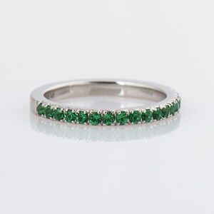 May include: A silver band ring with a row of small, green gemstones.