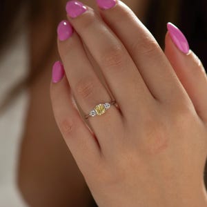 K&ouml;nnte beinhalten: Ein dreisteiniger Ring mit einem gelben Mittelst&uuml;ck und zwei kleineren wei&szlig;en Steinen auf jeder Seite. Der Ring ist in Wei&szlig;gold gefasst.