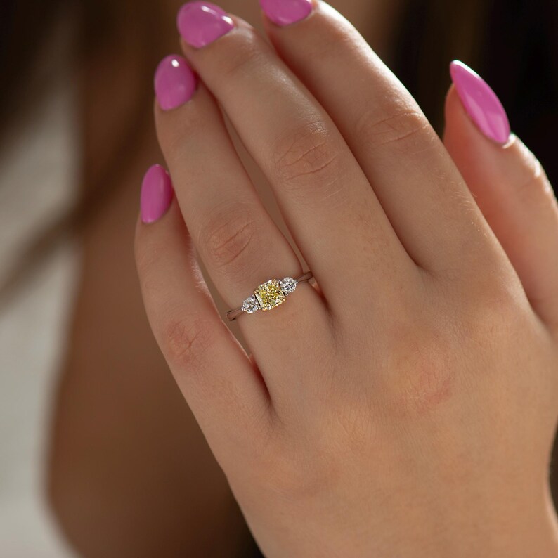 K&ouml;nnte beinhalten: Ein dreisteiniger Ring mit einem gelben Mittelst&uuml;ck und zwei kleineren wei&szlig;en Steinen auf jeder Seite. Der Ring ist in Wei&szlig;gold gefasst.