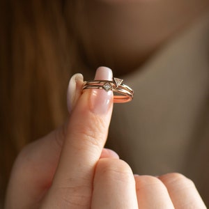 May include: Two gold rings with small triangular diamonds. The rings are stacked on top of each other.