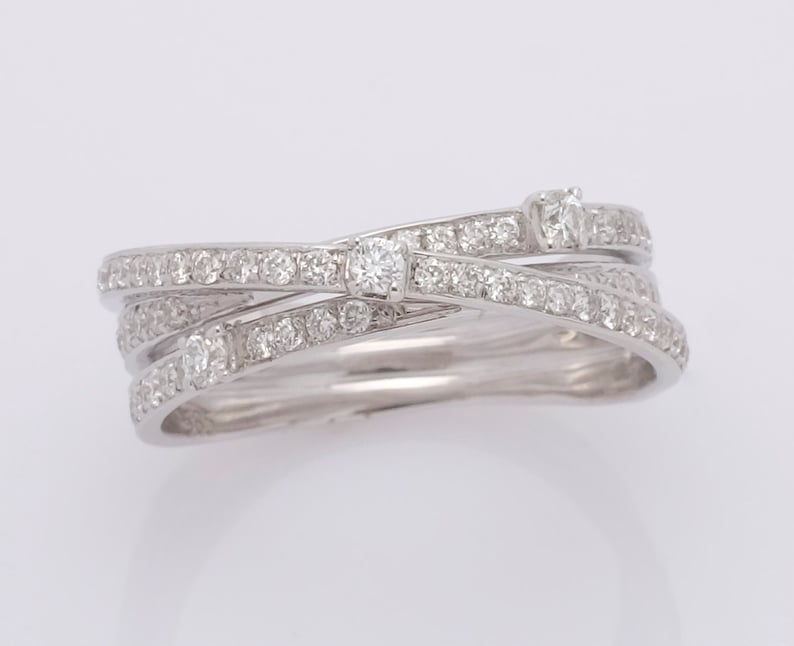 May include: A silver ring with three bands of diamonds that are intertwined. The ring has a larger diamond in the center.