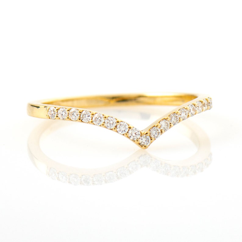 May include: A delicate gold band ring with a V-shaped row of small diamonds.