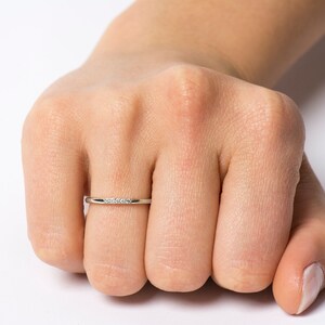 Op de afbeelding: Een dunne zilveren bandring met een rij kleine diamanten in het midden.