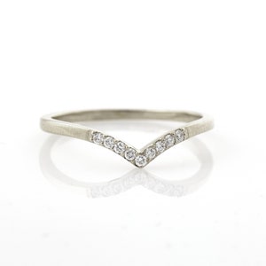May include: A silver band ring with a V-shaped row of small diamonds.
