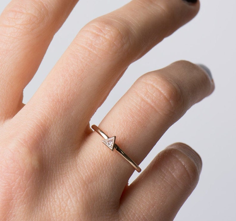 May include: A delicate gold ring with a small triangular diamond set in the center.