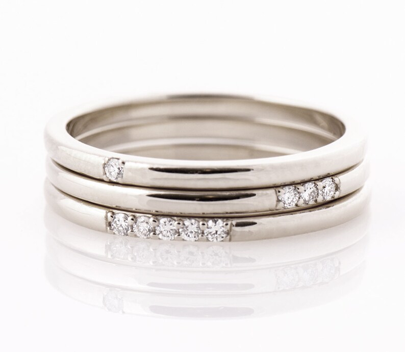Op de afbeelding: Drie zilveren stapelringen met kleine diamanten die in de ringen zijn gezet.