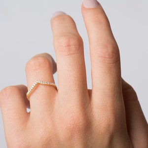 May include: A gold band ring with a V-shaped row of small diamonds.