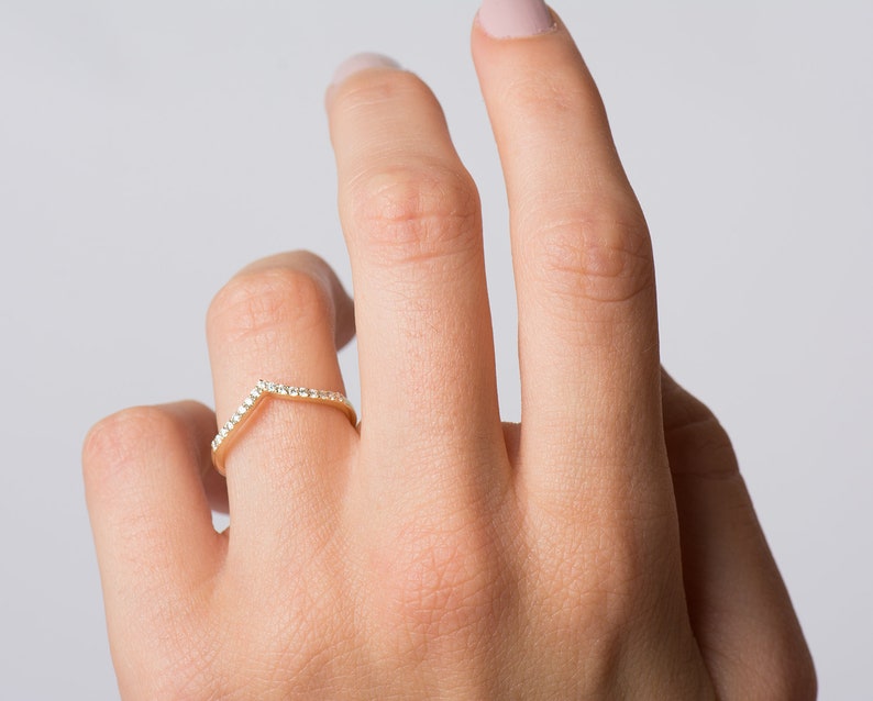 May include: A gold band ring with a V-shaped row of small diamonds.
