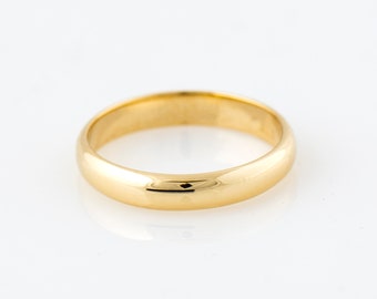 May include: A polished gold band ring. The ring has a smooth, rounded design and a bright, reflective surface. The ring is set against a white background, highlighting its simple elegance. This classic ring is suitable for various occasions.