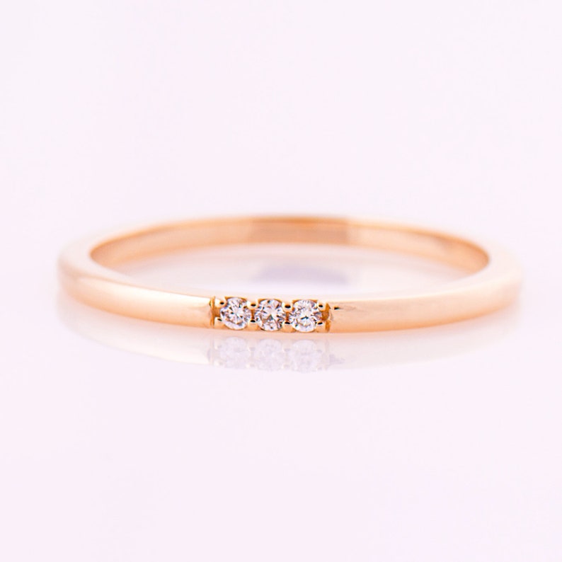 May include: A simple gold band ring with three small diamonds set in a row.
