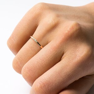 May include: A thin gold band ring with three small diamonds set in a row.
