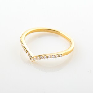 May include: A gold band ring with a V-shaped row of small diamonds.