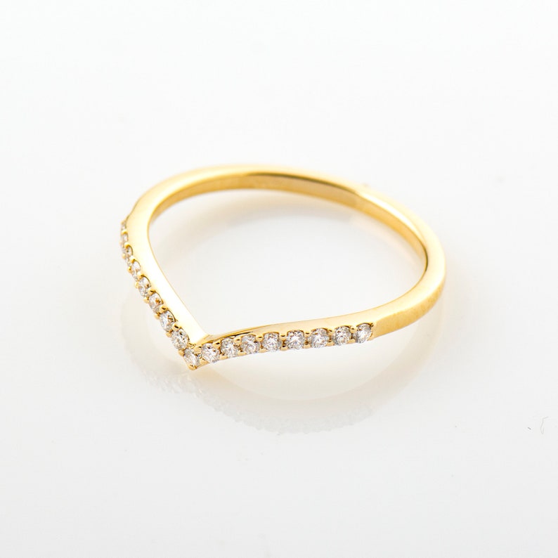 May include: A gold band ring with a V-shaped row of small diamonds.