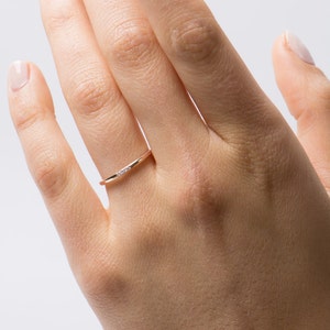 May include: A delicate gold band ring with a small row of diamonds set in the center.