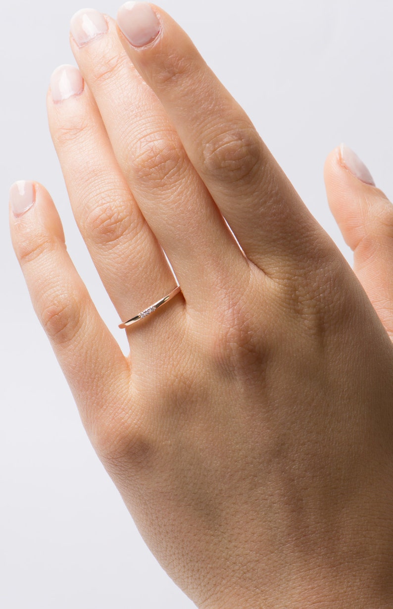 May include: A delicate gold band ring with a small row of diamonds set in the center.