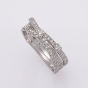 May include: A silver ring with three bands of diamonds that are intertwined. The diamonds are set in a pave setting.