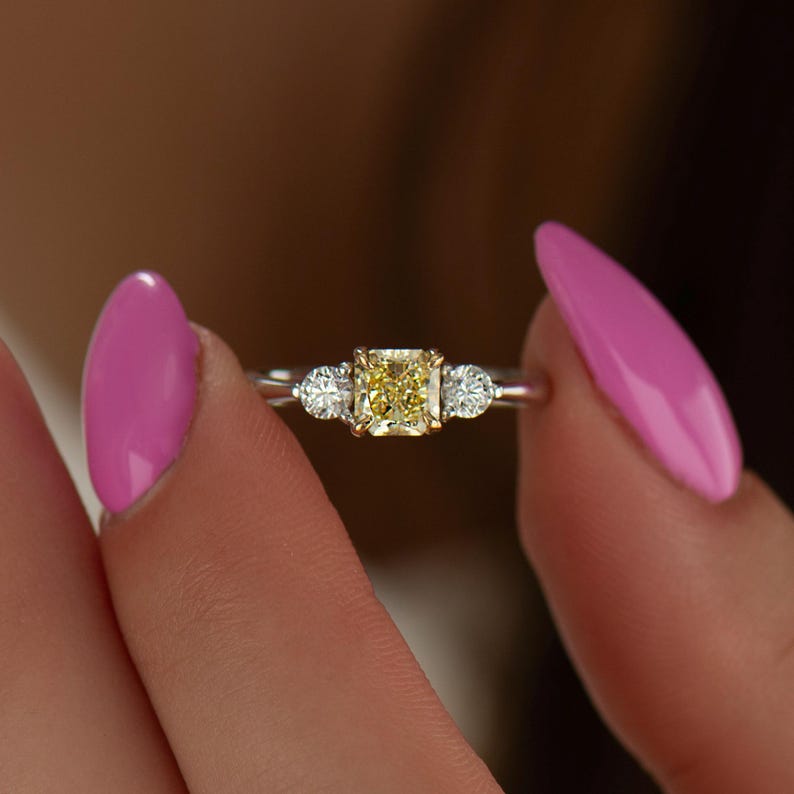 K&ouml;nnte beinhalten: Ein goldener Ring mit einem gelben Diamanten in der Mitte und zwei kleineren Diamanten an jeder Seite.