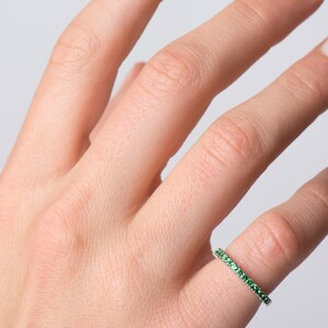 May include: A delicate ring with a band of small green gemstones.