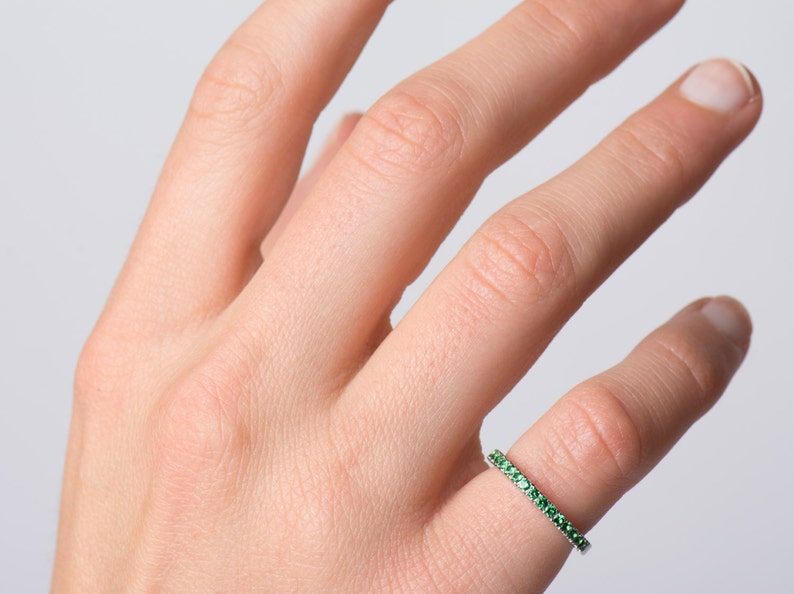 May include: A delicate ring with a band of small green gemstones.