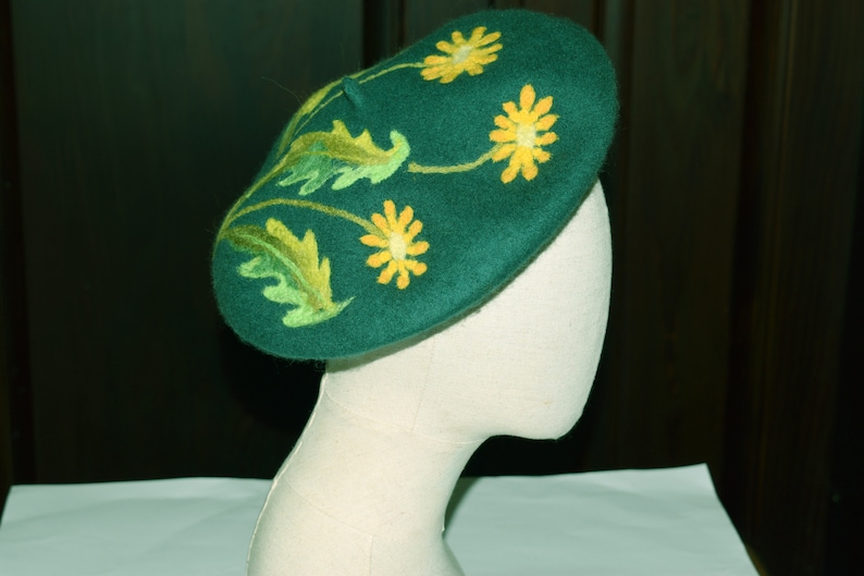 May include: A green felt beret with yellow embroidered flowers and green leaves.