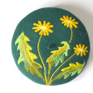 May include: A dark green felt beret with yellow and green embroidered dandelions.