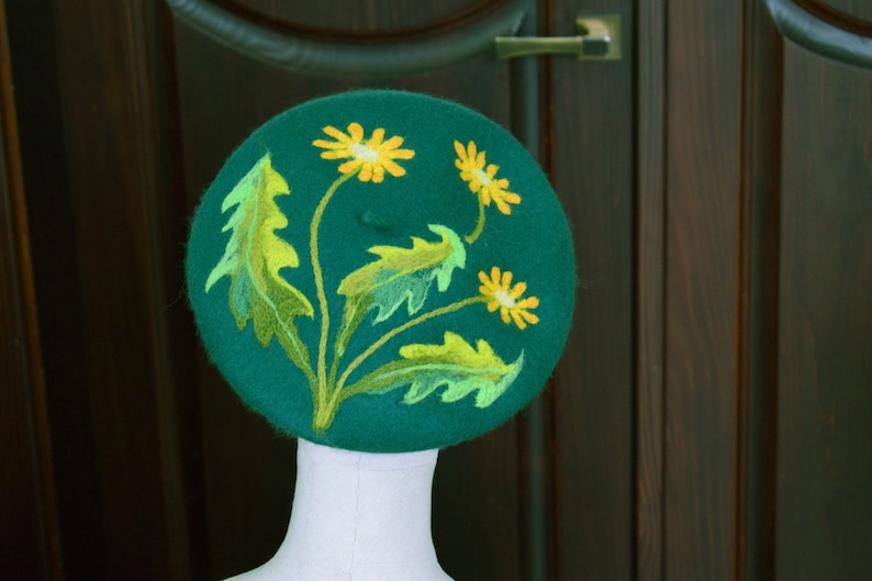 May include: A green felt beret with yellow and green embroidered flowers.