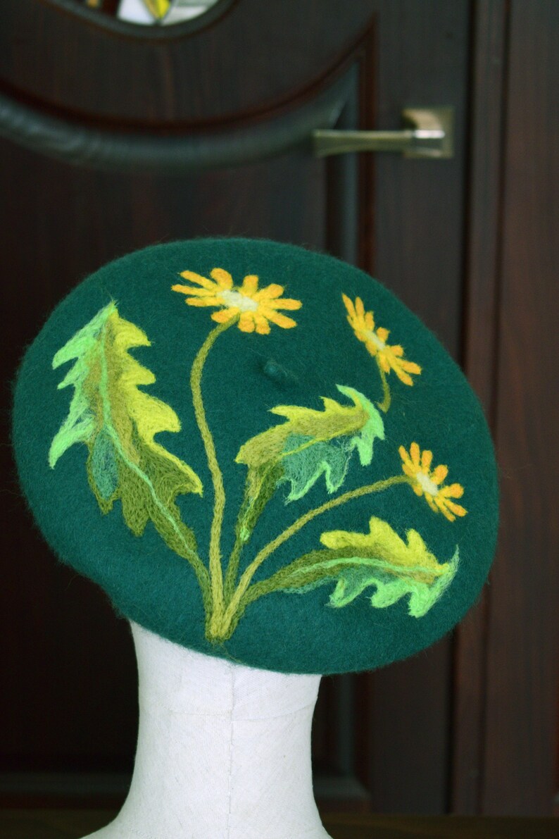 May include: A green felt beret with yellow and green embroidered dandelions.