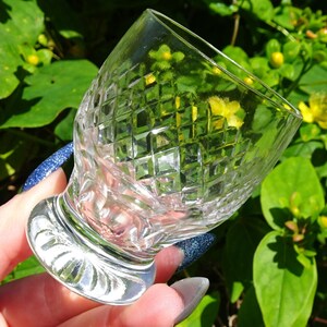 Op de afbeelding: Een helder glazen shotglas met een diamantpatroon. Het glas heeft een korte steel en een brede basis.