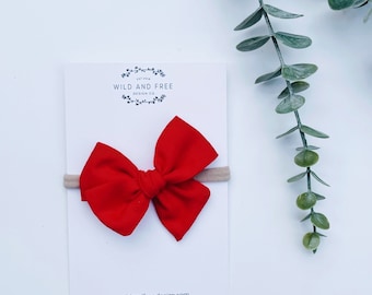 Puede incluir: Diadema de lazo de tela roja sobre una tarjeta blanca con el texto "Wild and Free Design Co."