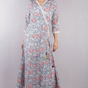 May include: A blue and pink floral print wrap dress with a long skirt and three-quarter sleeves. The dress has a tie at the waist and a tassel detail.