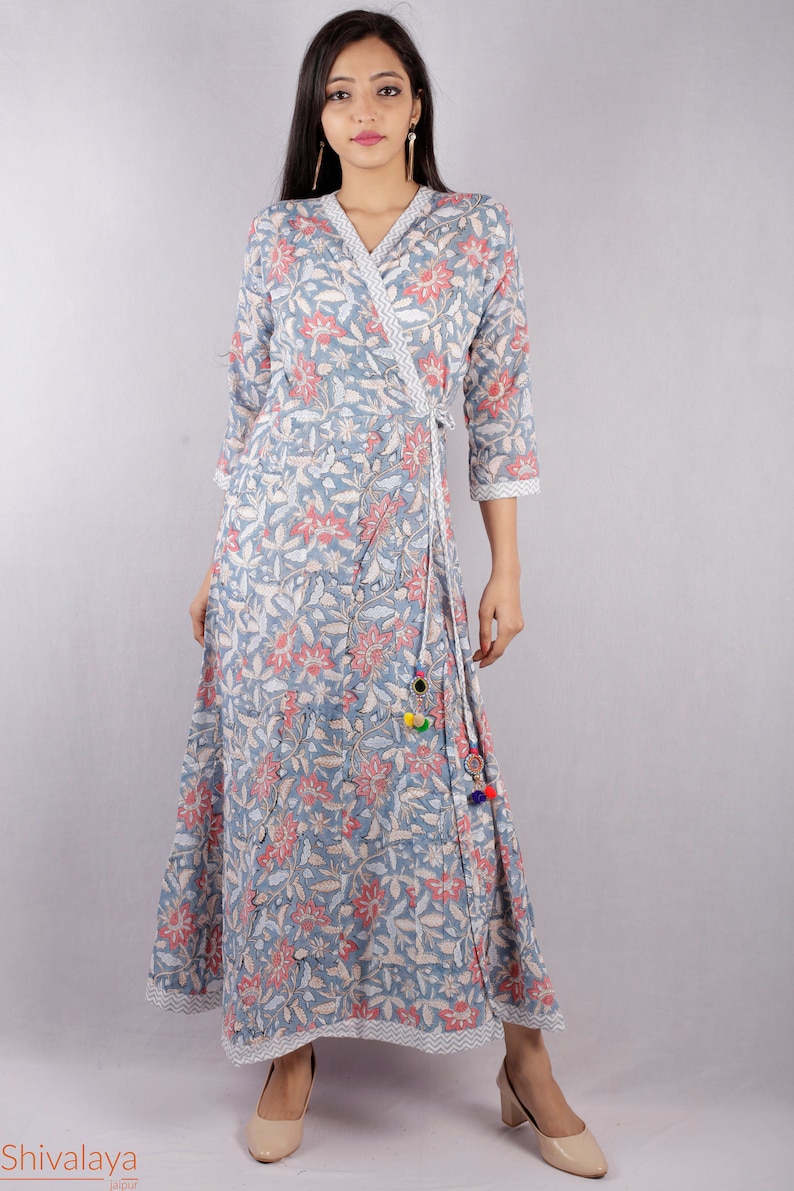May include: A blue and pink floral print wrap dress with a long skirt and three-quarter sleeves. The dress has a tie at the waist and a tassel detail.