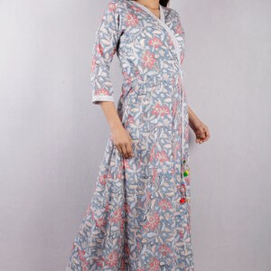 May include: A long, blue and pink floral print wrap dress with a tassel tie. The dress has a V-neckline and 3/4 sleeves.