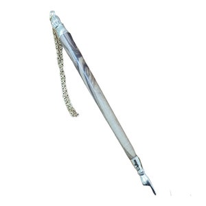 Może przedstawiać: Pióro do pisania ze srebra i drewna z łańcuszkiem przymocowanym do górnej części. Pióro ma spiczasty grot i drewniany trzonek z srebrną końcówką.