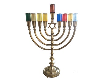 May include: A gold menorah with nine candle holders, each with a colored glass candle. The menorah has a Star of David at the top.