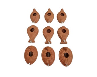 May include: Ten terracotta oil lamps, some with a bird design and others with a circular design. The lamps are all brown and have a hole in the top for a wick.
