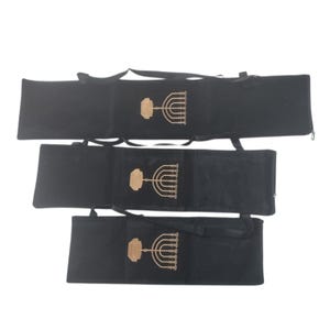 Puede incluir: Tres bolsas de terciopelo negro con diseños de menorá bordados en oro. Cada bolsa tiene una cremallera y una correa.