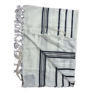 Op de afbeelding: Witte gebedssjaal met zwarte en grijze strepen en decoratieve kwastjes. De sjaal heeft een rechthoekige vorm en is opgevouwen. De hoeken hebben geborduurde vierkante ontwerpen. De stof lijkt licht van gewicht.