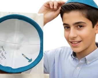 Könnte beinhalten: Eine türkisfarbene Kippa mit weißem Innenfutter und türkisfarbenem Rand. Die Kippa hat Text und eine Grafik auf der Innenseite. Die Person auf dem Bild trägt eine passende türkisfarbene Kippa.