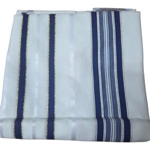 May include: Folded white fabric with vertical stripes in navy blue and gold. The fabric has a textured appearance and is folded neatly. The design features alternating stripes of varying widths, creating a visually appealing pattern.