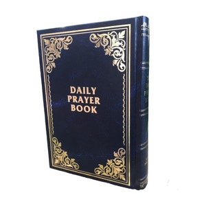Può includere: Un libro di preghiere rilegato in pelle blu con dettagli dorati e il titolo "DAILY PRAYER BOOK" sulla copertina.