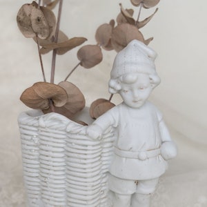Figurine ancienne de garçon en biscuit de porcelaine. Garçon en céramique avec panier. Porcelaine de collection. figurine vintage vase en porcelaine blanche.