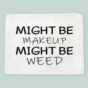 May include: White canvas makeup bag with black text that reads "Might be makeup might be weed".