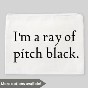 May include: White zippered pouch with the text "I'm a ray of pitch black" in black. The pouch has a rectangular shape and a zipper closure. The phrase is written in a bold, sans-serif font.