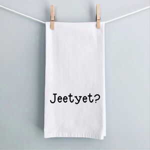 May include: White kitchen towel with the text "Jeetyet?" printed in black.