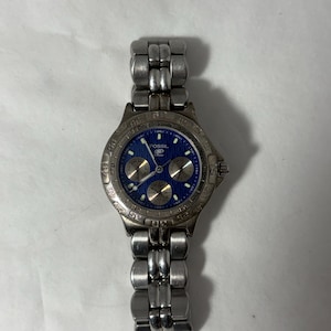 Puede incluir: Reloj Fossil plateado con esfera azul y tres subesferas. El reloj tiene una correa de acero inoxidable y una esfera redonda con marcadores y agujas plateadas. Diseño clásico.
