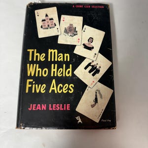 May include: Vintage book titled "The Man Who Held Five Aces" by Jean Leslie. The cover is black with yellow text and features playing cards with various illustrations. A Crime Club Selection is printed at the top.
